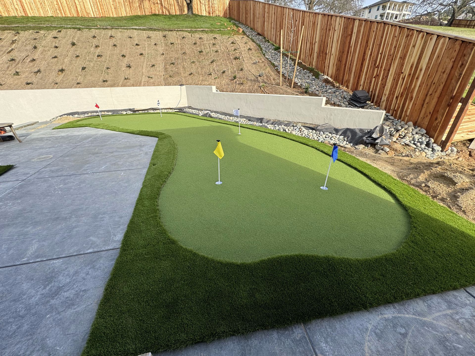 There is a putting green in the backyard of a house.