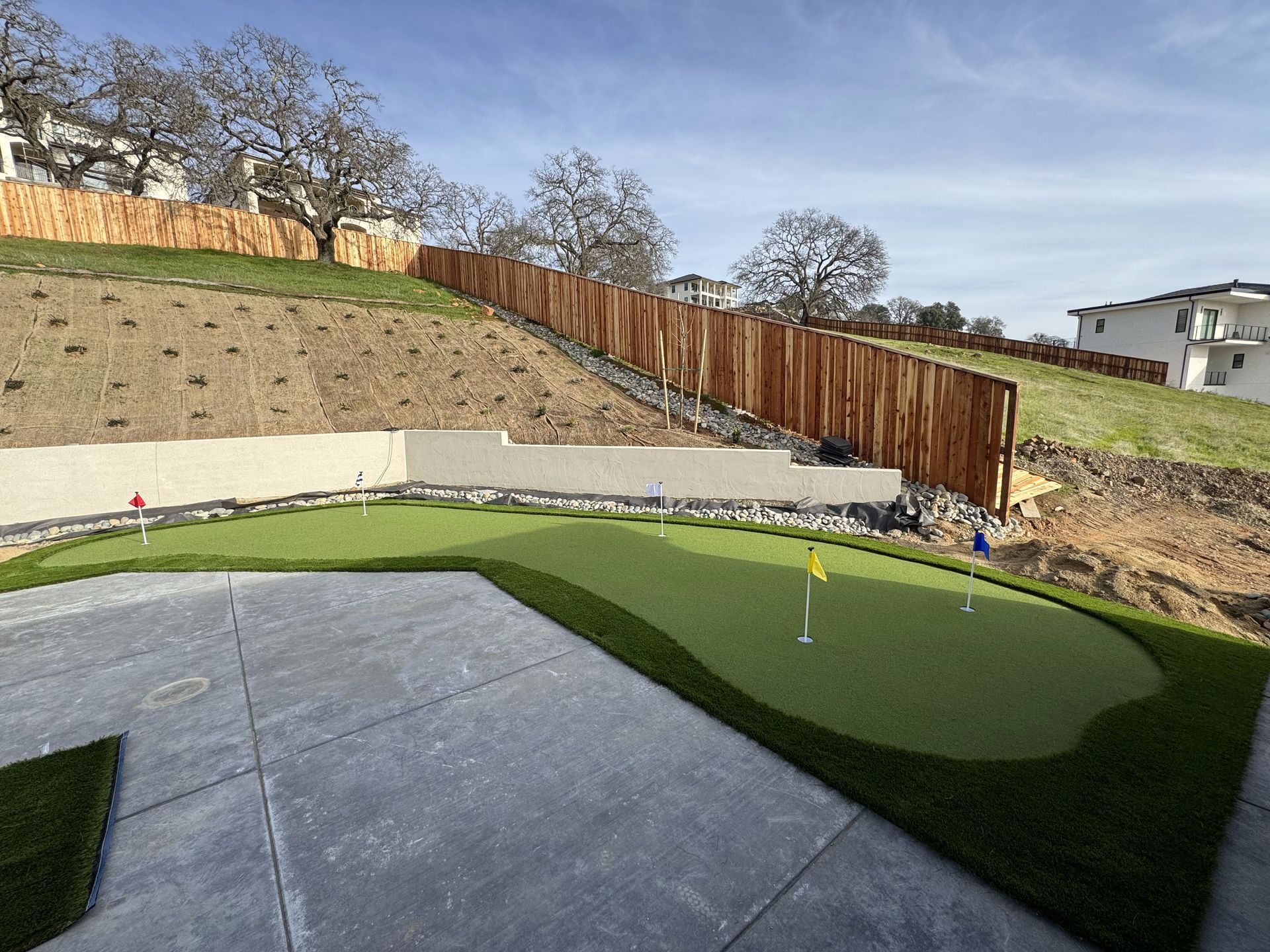 A backyard with a putting green and a wooden fence