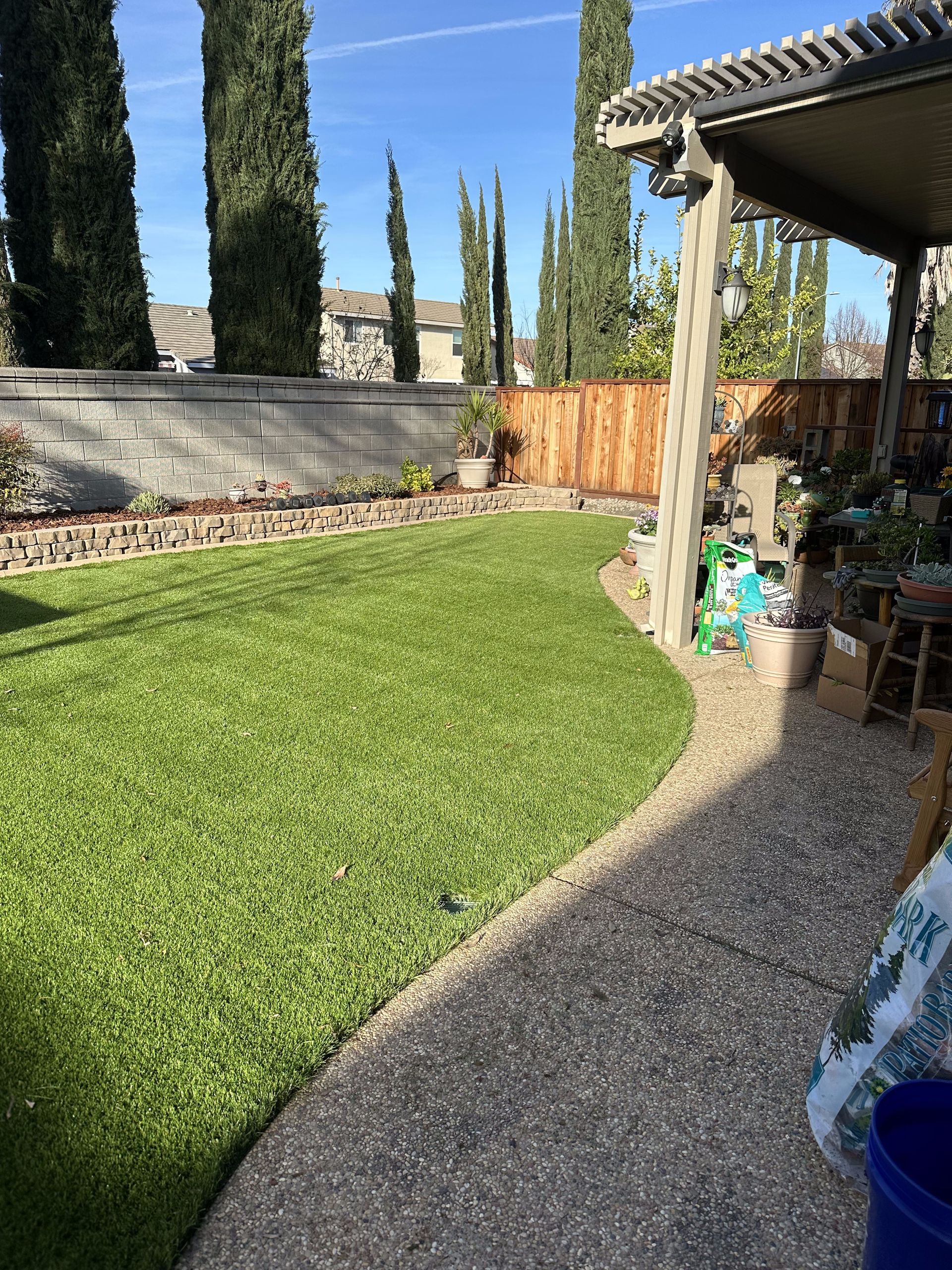 A backyard with a lush green lawn and a pergola.