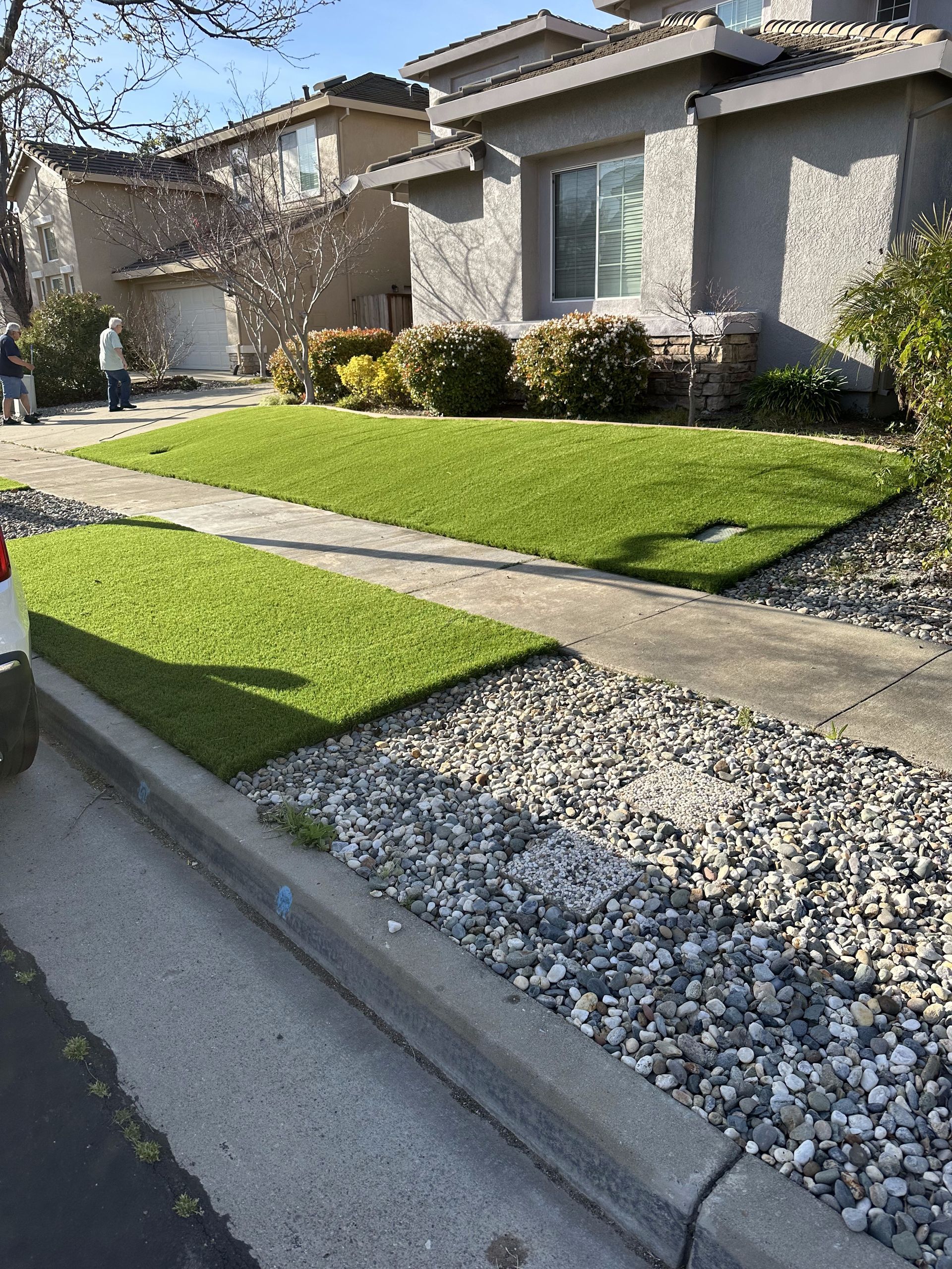 A car is parked in front of a house with a lush green lawn.