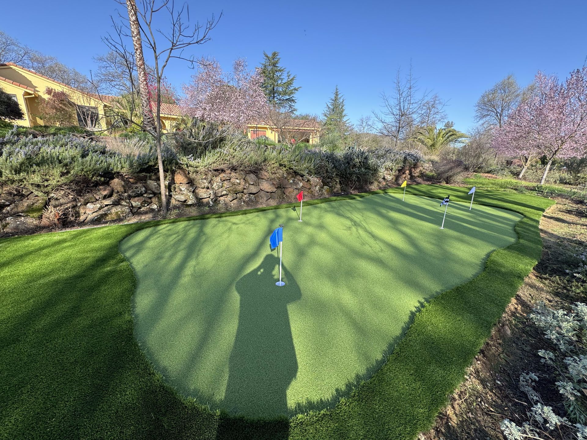 A golf course with a shadow of a person on the green.