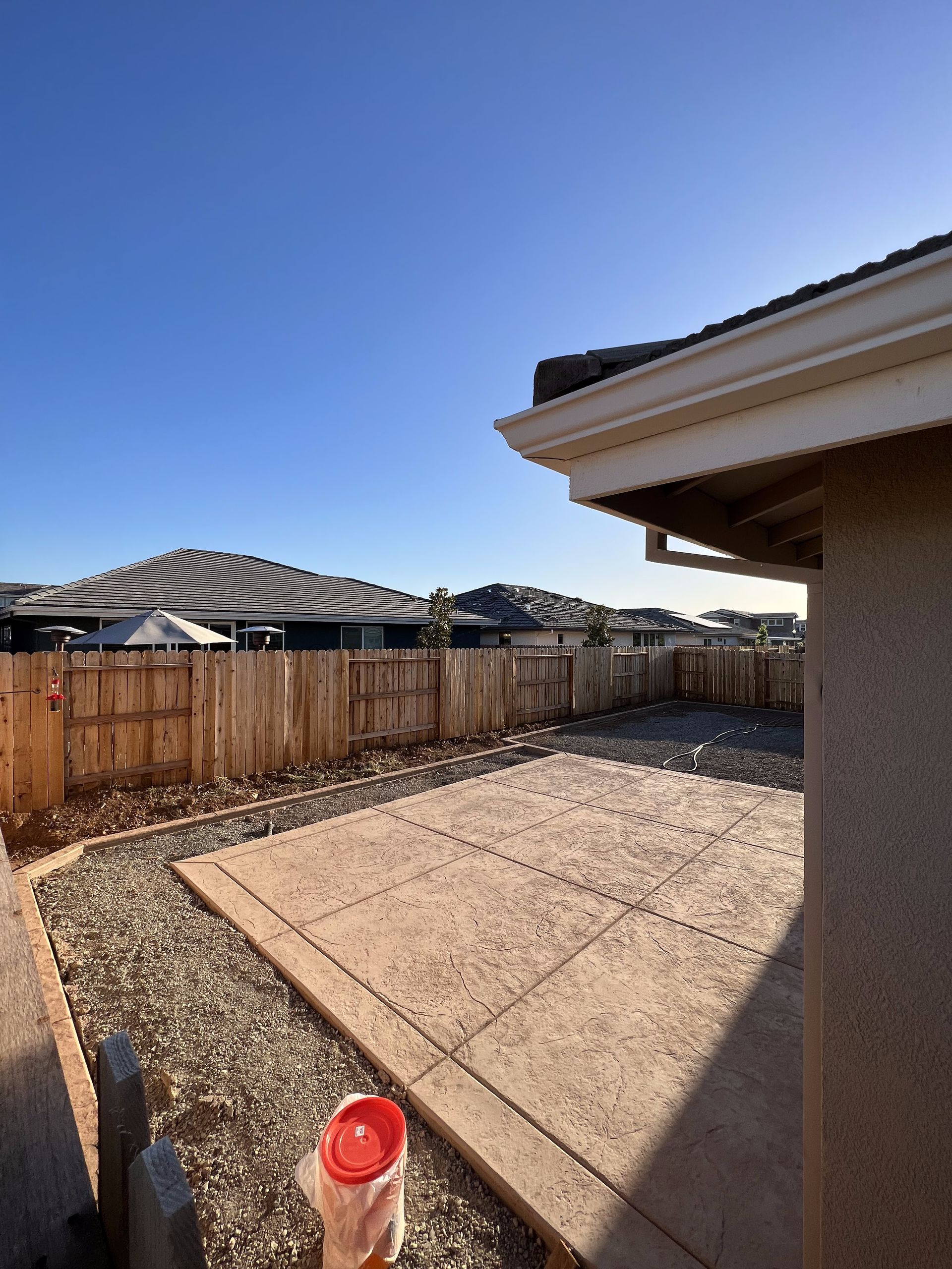 A backyard with a fence and a house in the background