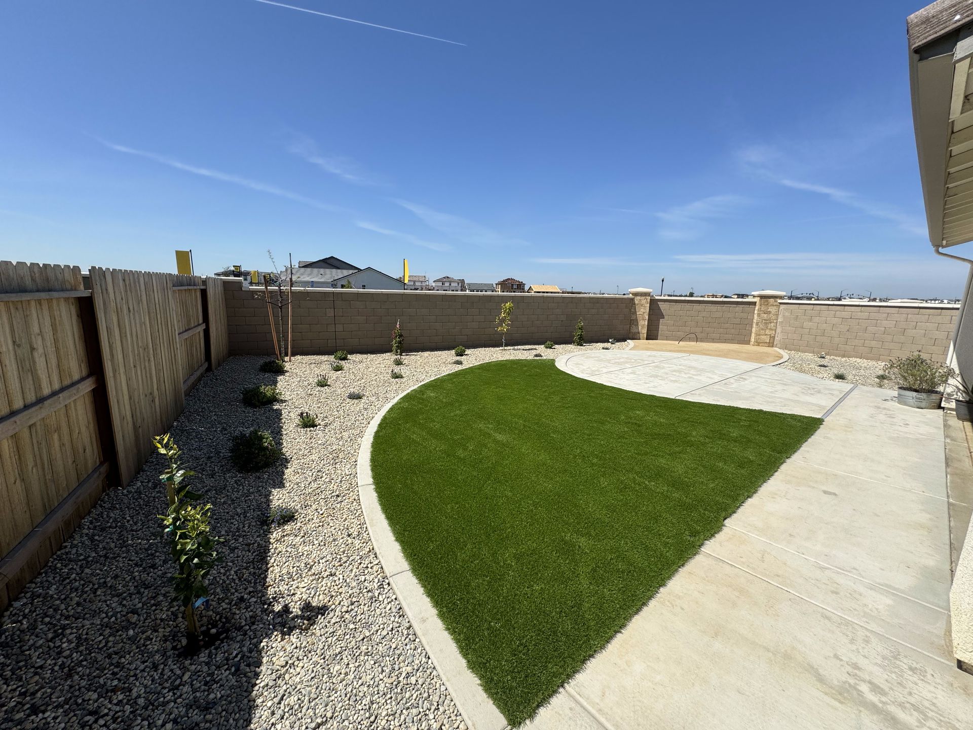 A backyard with a concrete walkway and a lush green lawn.