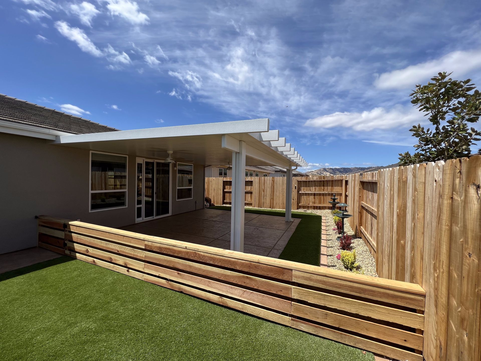 A house with a covered patio and a wooden fence surrounding it.
