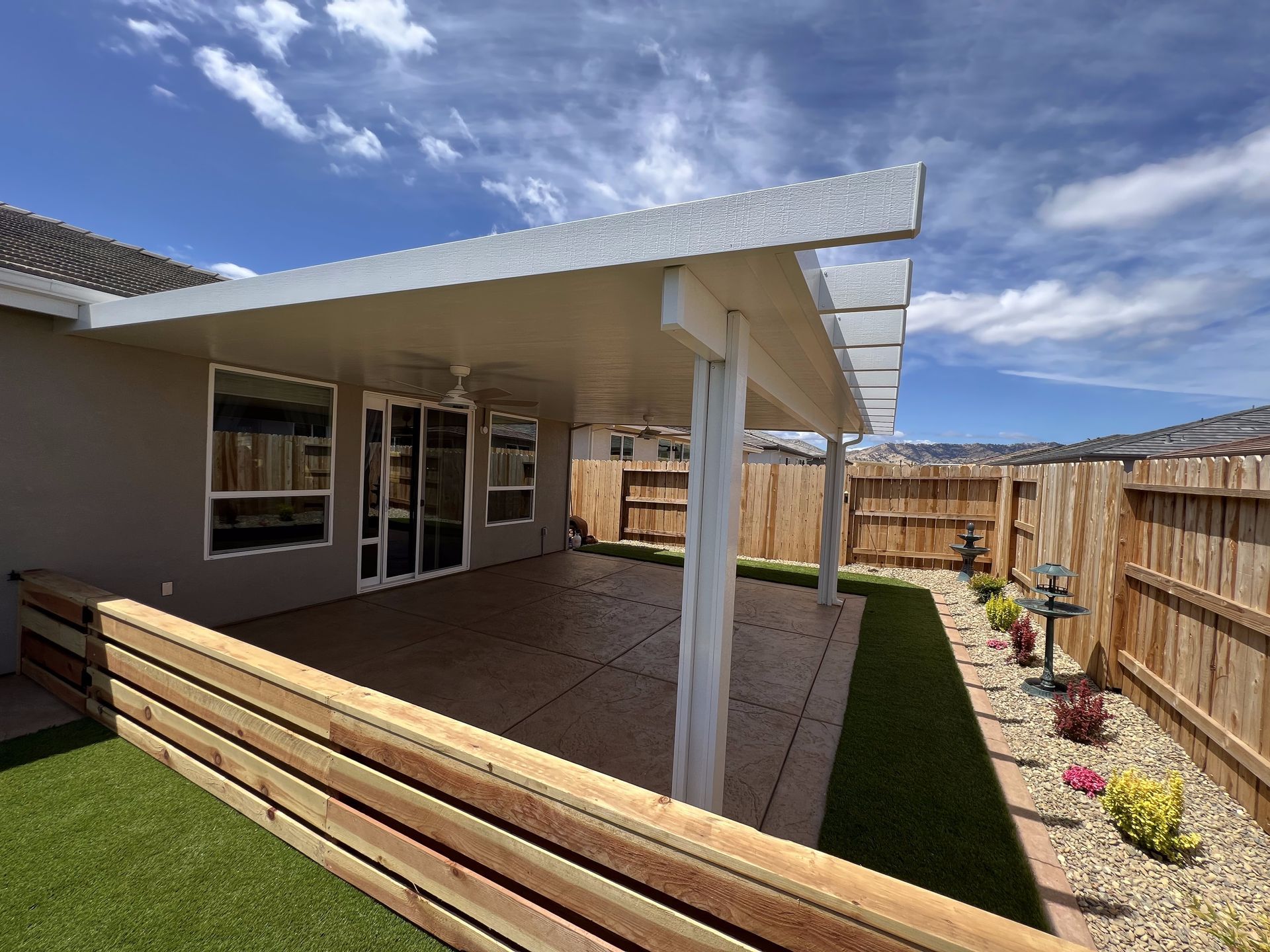 The backyard of a house with a pergola and a wooden fence