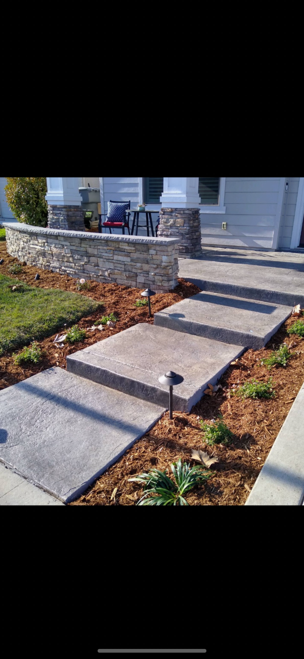 A concrete walkway with steps leading up to a house.