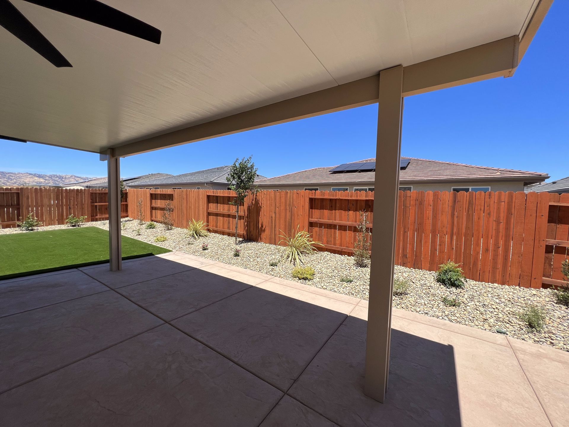 A patio with a ceiling fan and a wooden fence