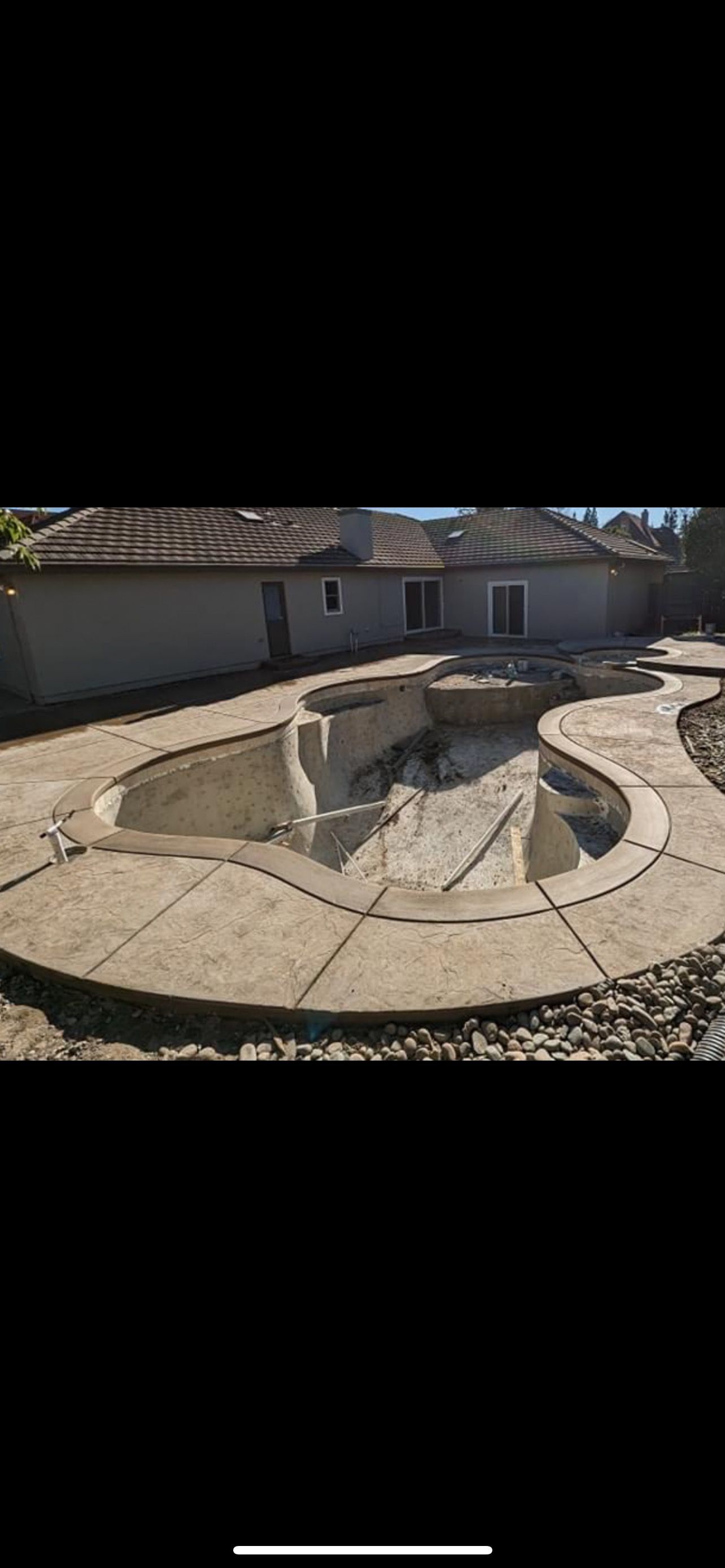 A swimming pool is being built in the backyard of a house.