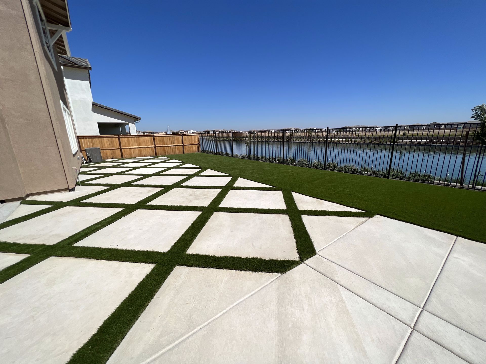A patio with a fence and a lake in the background