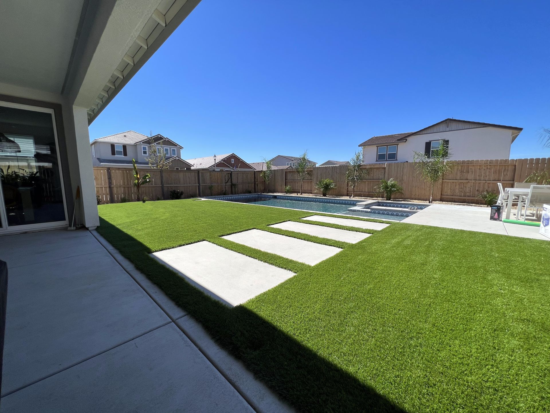 A large backyard with a swimming pool and a patio.