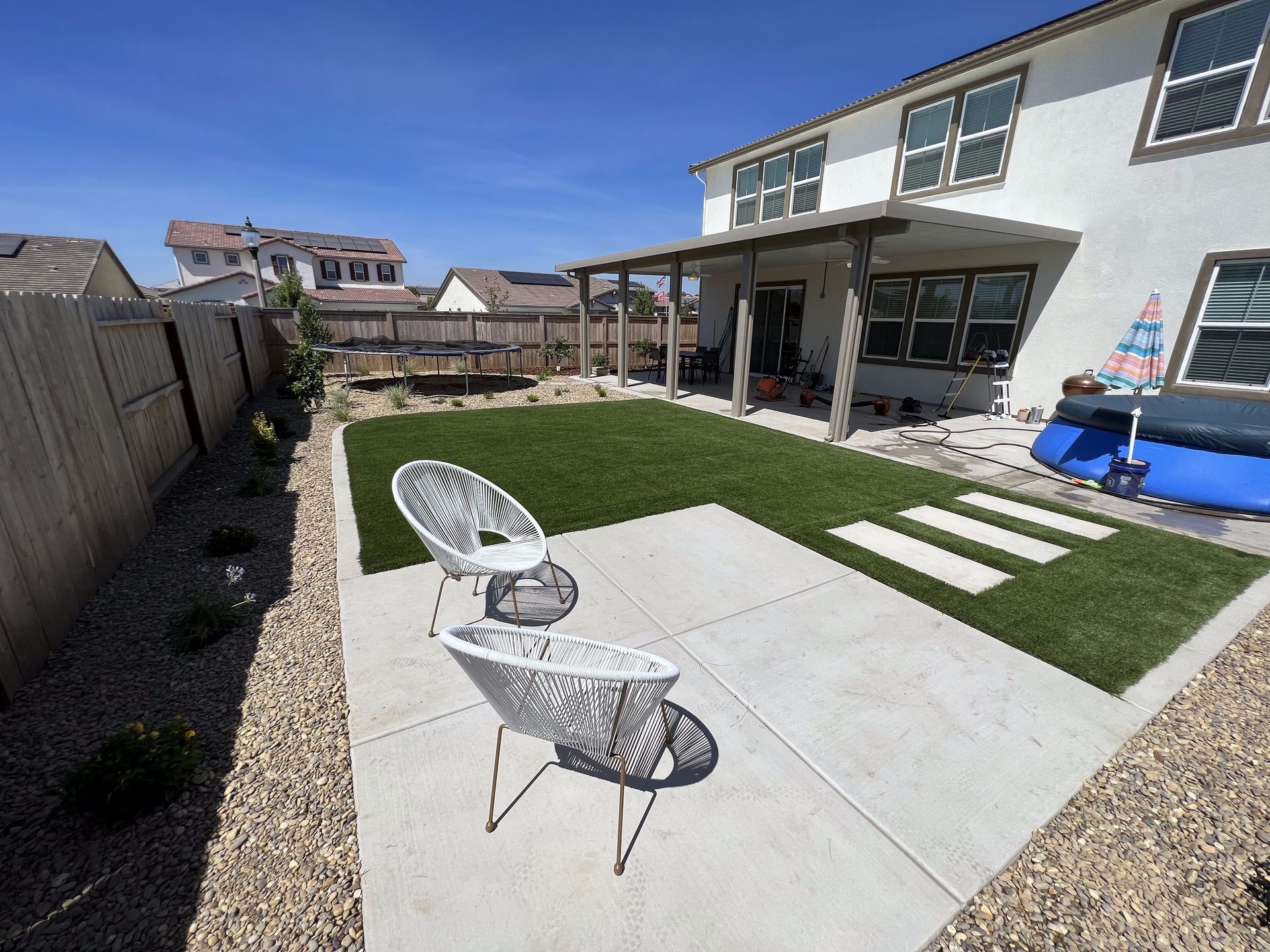 A patio with chairs and a table in front of a house.