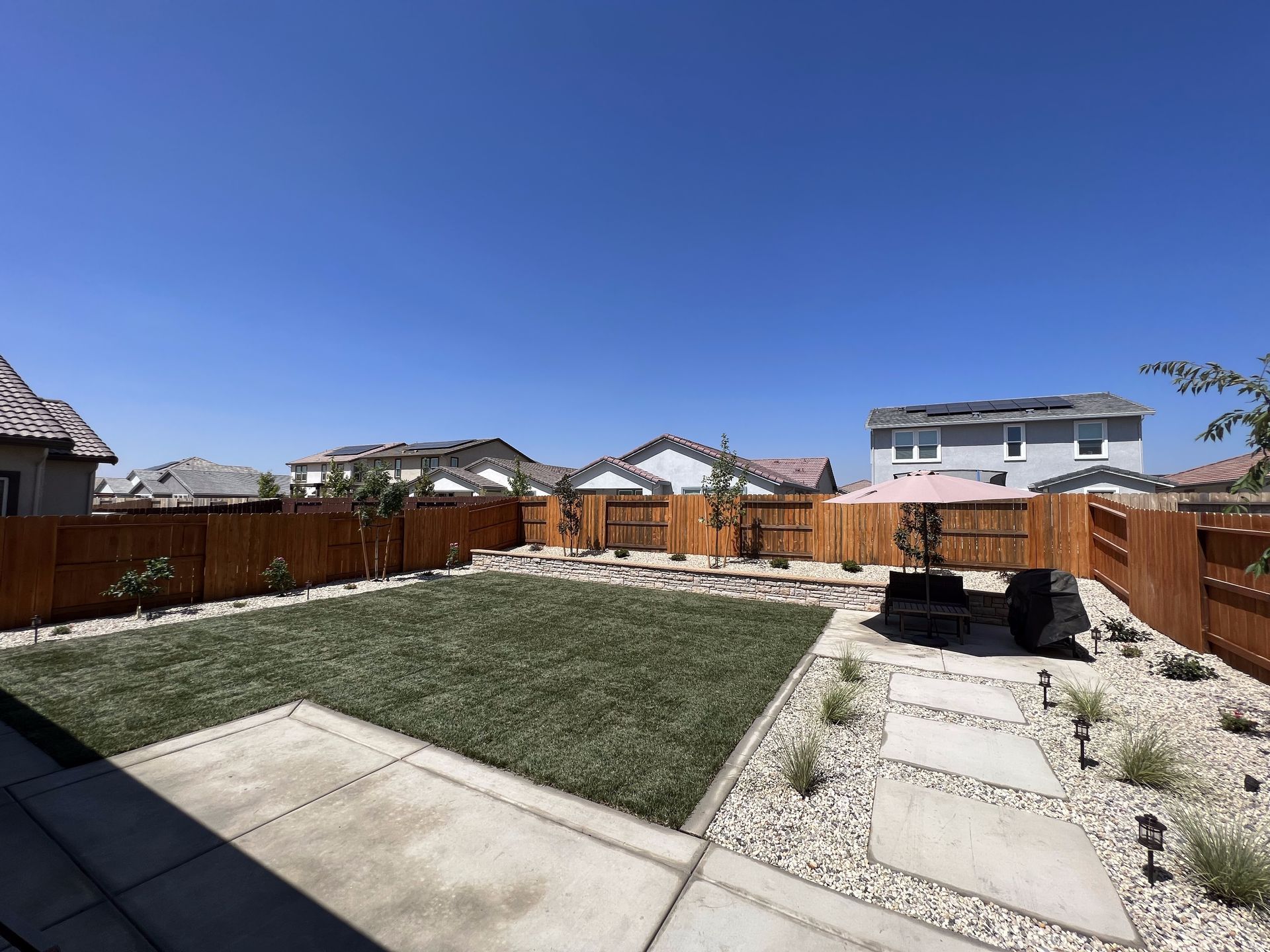 A backyard with a wooden fence and a patio area