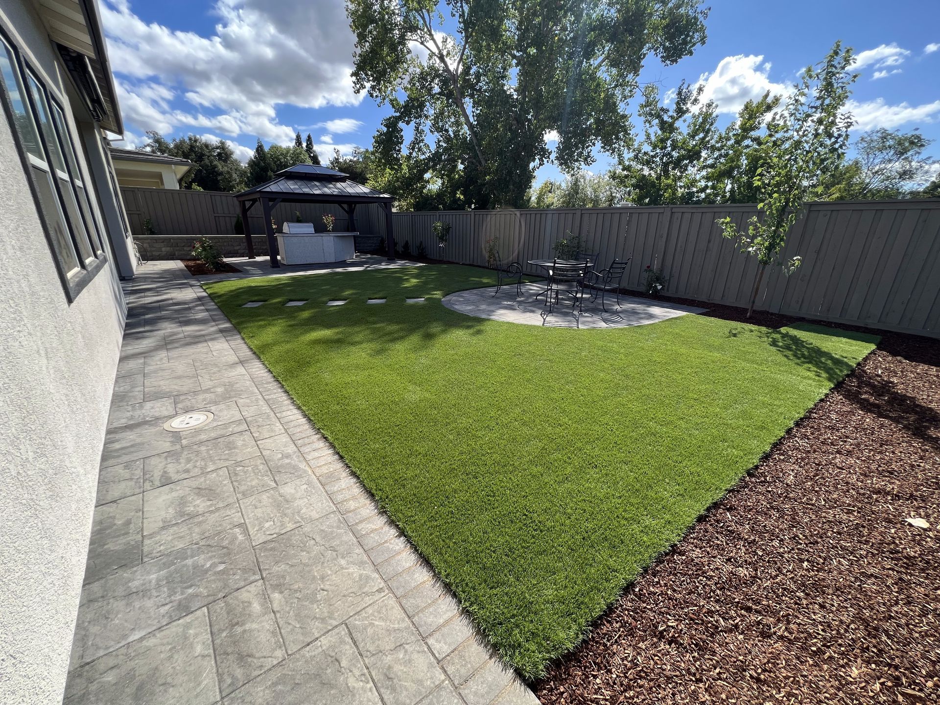 A backyard with a large lawn and a gazebo.