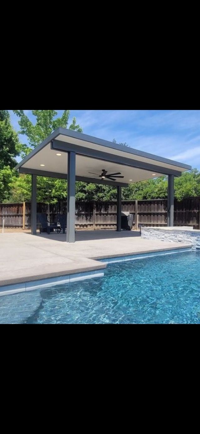 A covered patio next to a swimming pool with a ceiling fan.