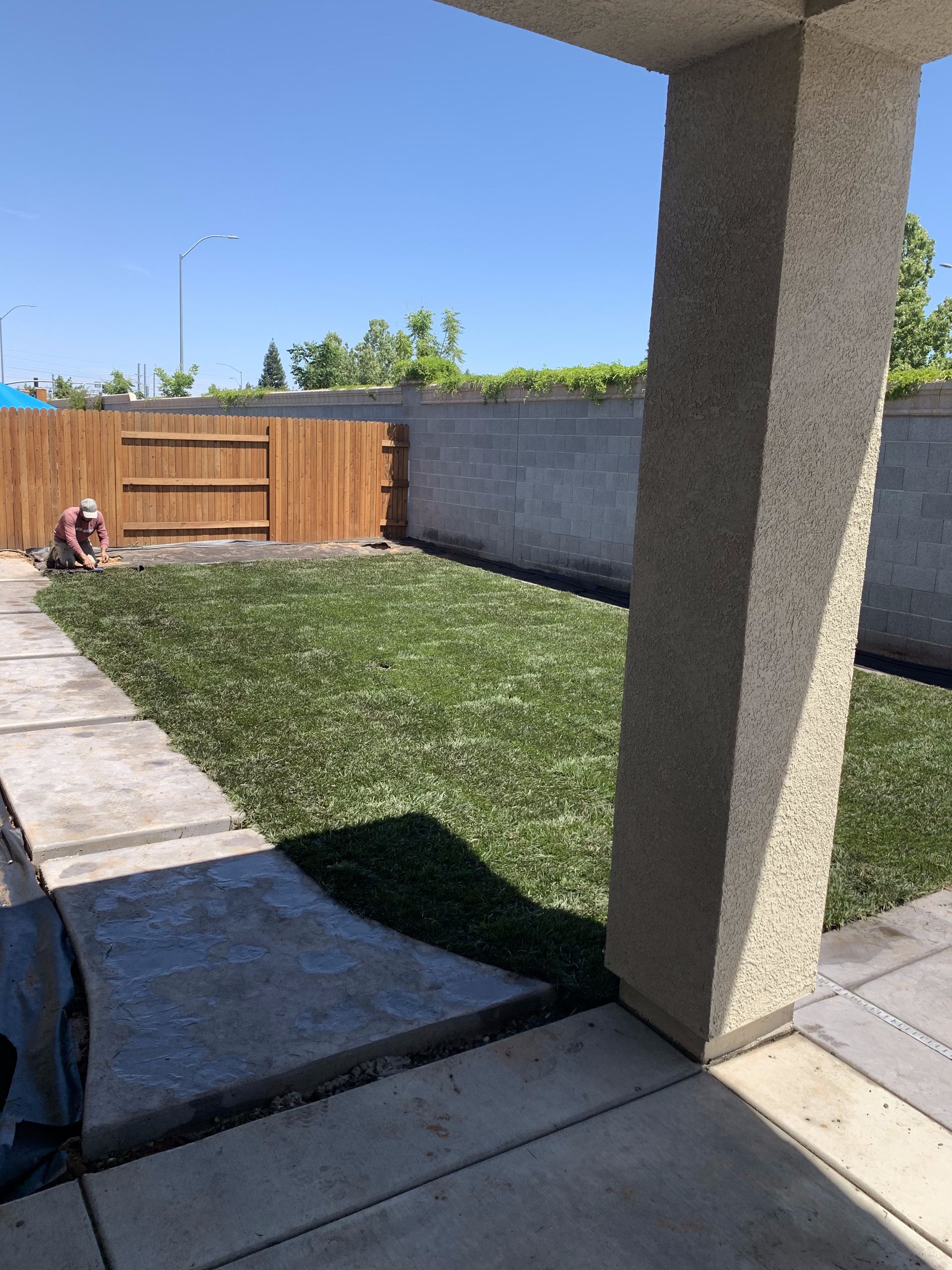 A man is working on a fence in the backyard of a house.