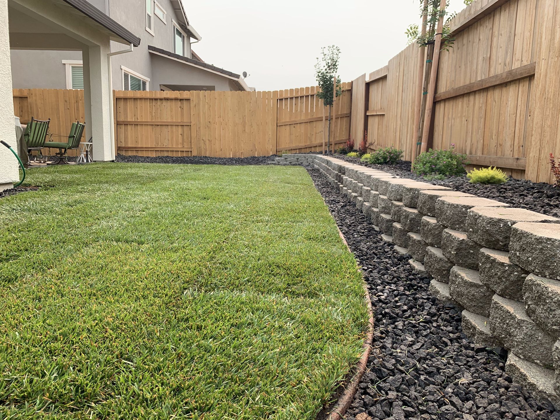 A backyard with a wooden fence and a stone wall.