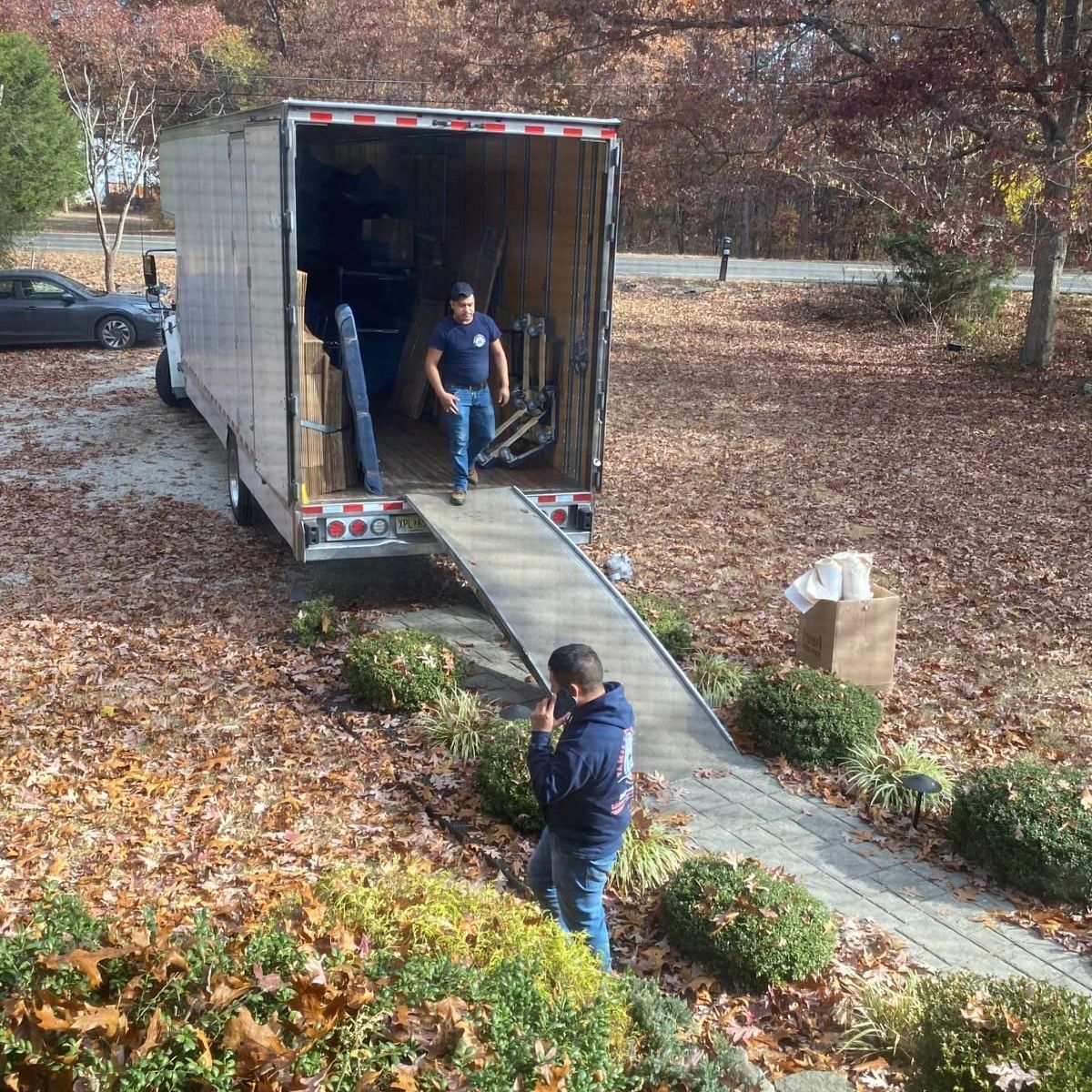 A man is talking on a cell phone in front of a moving truck