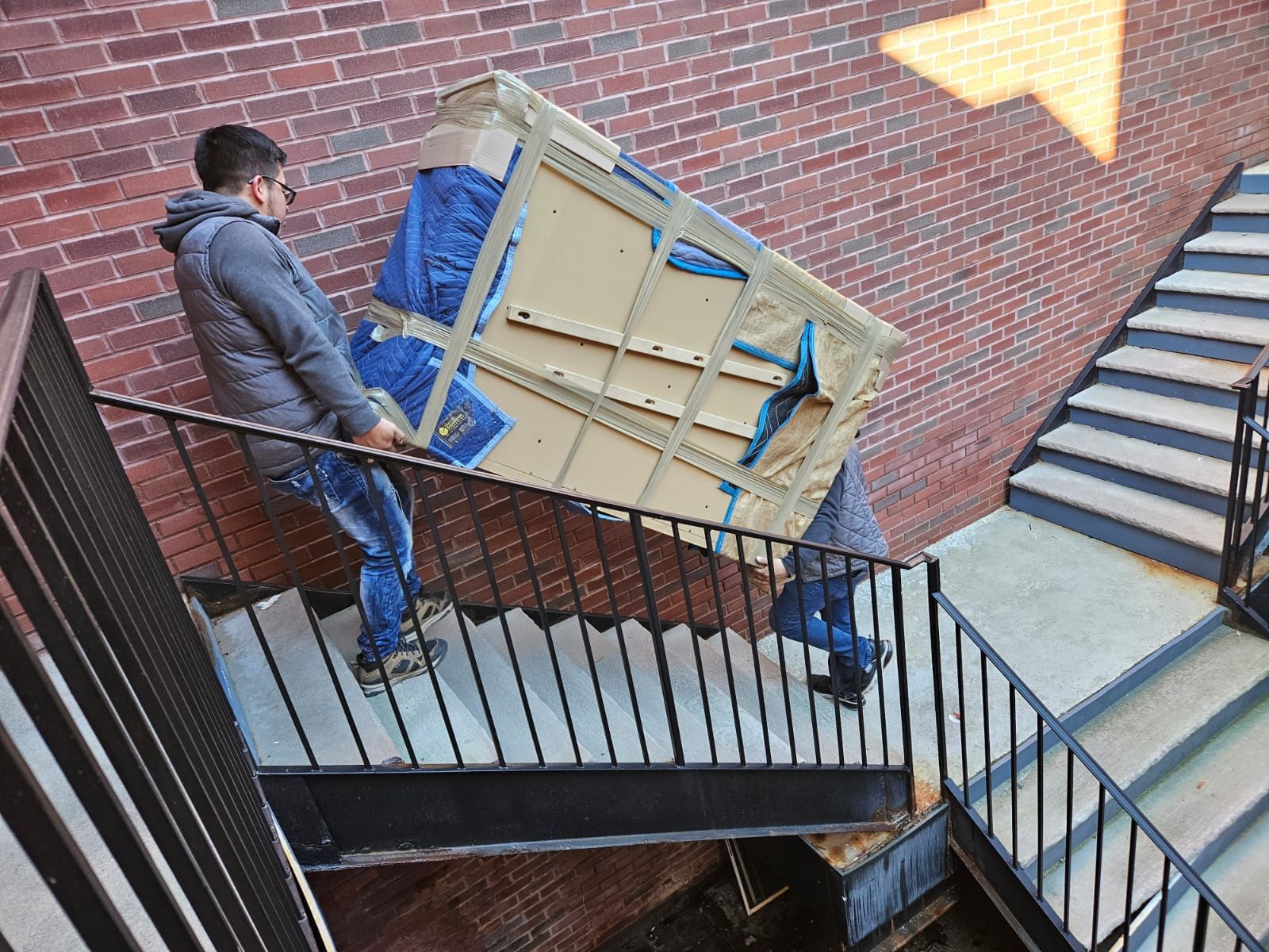 A man is carrying a piano up a set of stairs.