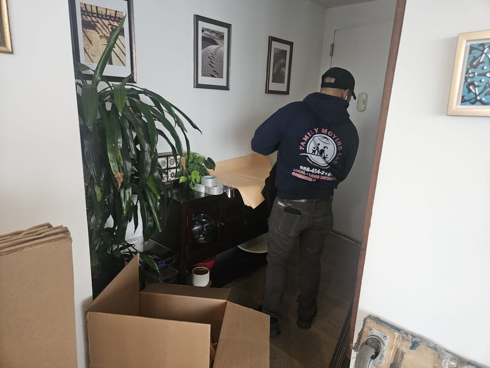 A man in overalls is holding a white table in a room.