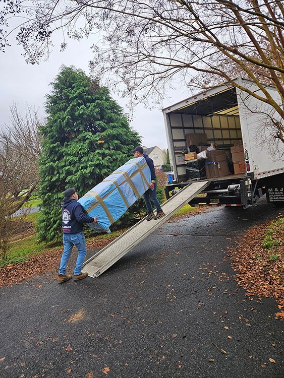Two men are carrying a large piece of furniture up a ramp into a truck.