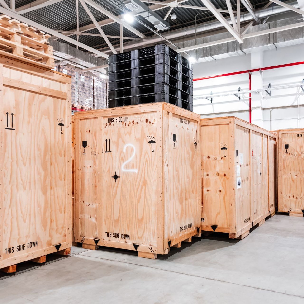 A warehouse filled with wooden crates and plastic pallets.