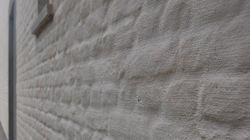 Een close-up van een witte bakstenen muur met een raam.