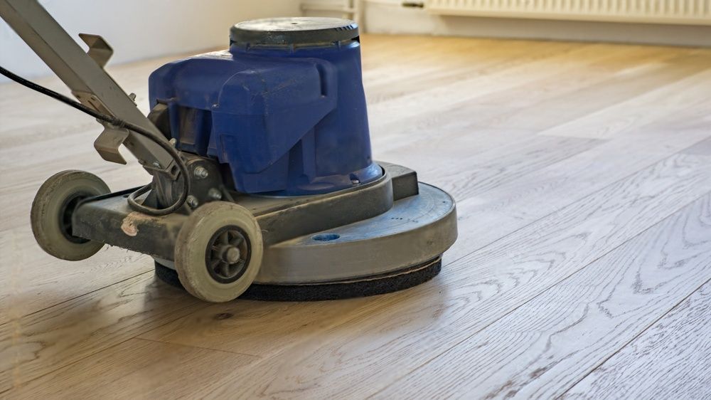 Een machine poetst een houten vloer in een kamer.