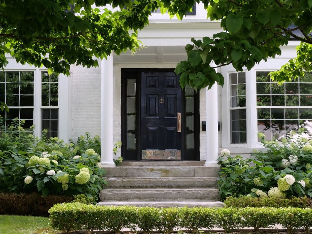 Een wit huis met twee zwarte garagedeuren en een grindoprit