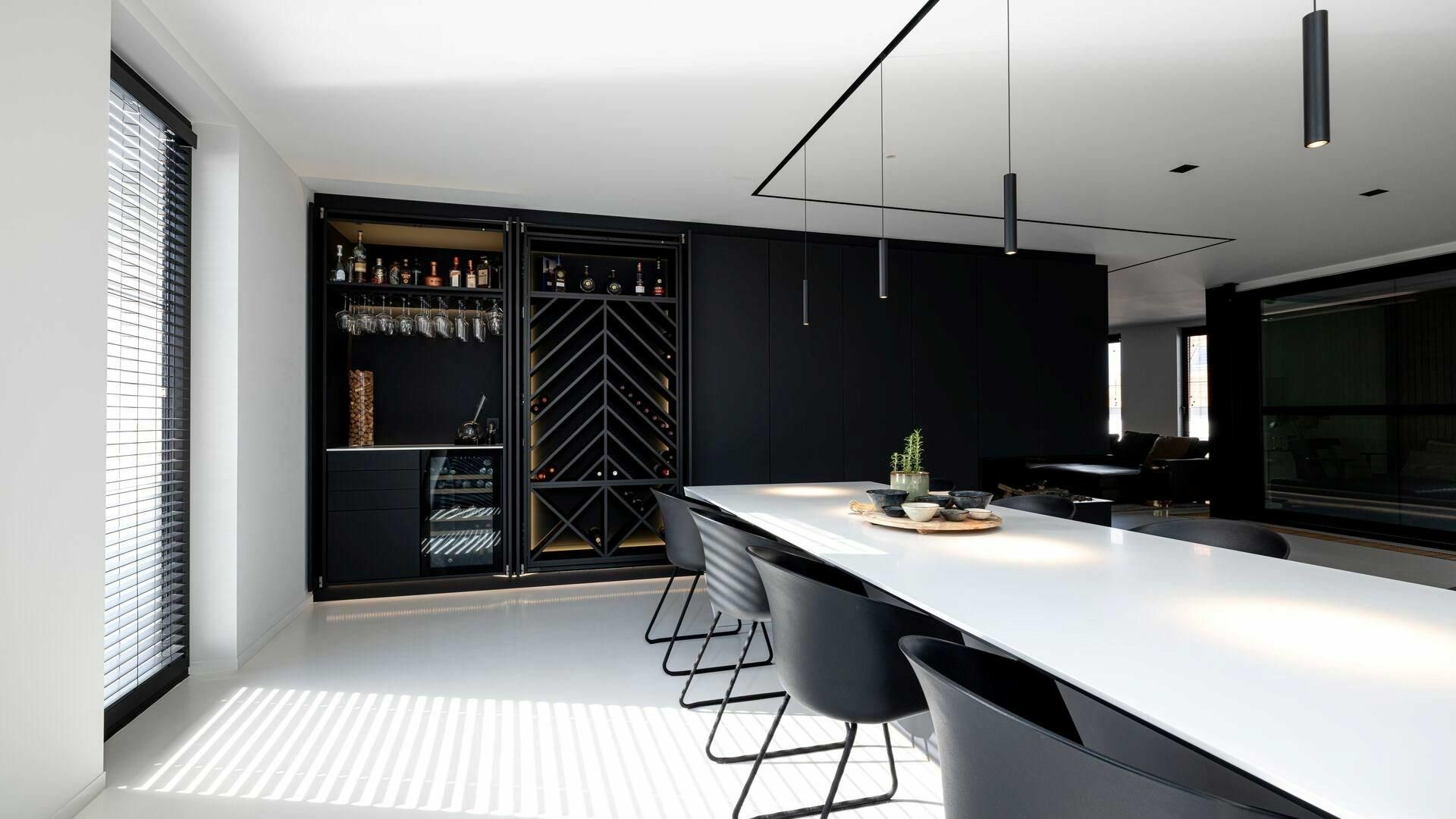 Een eetkamer met een lange witte tafel en zwarte stoelen.