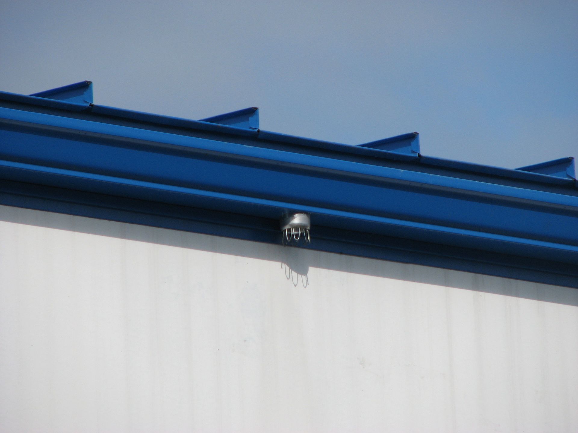 A blue gutter on the side of a building