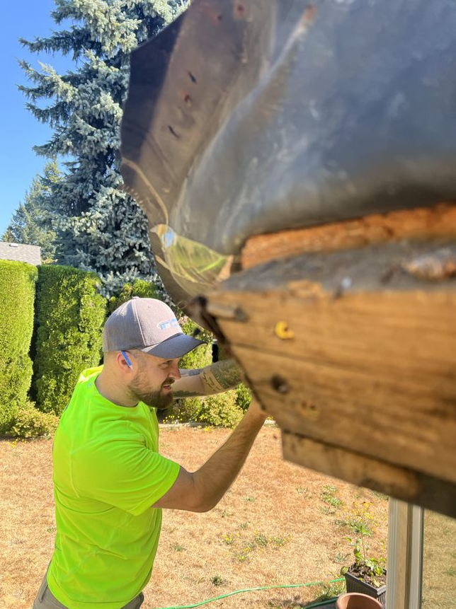 A man in a neon green shirt is working on a wooden structure.