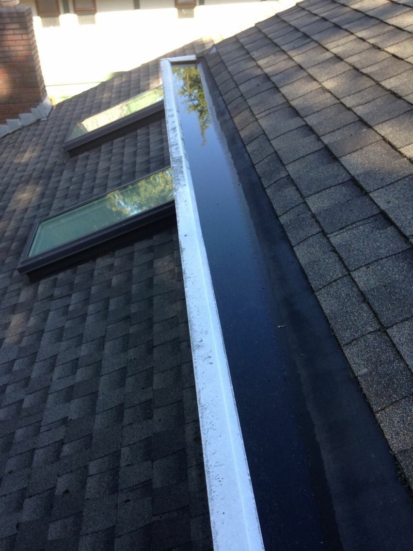 A roof with a skylight and a gutter on it.