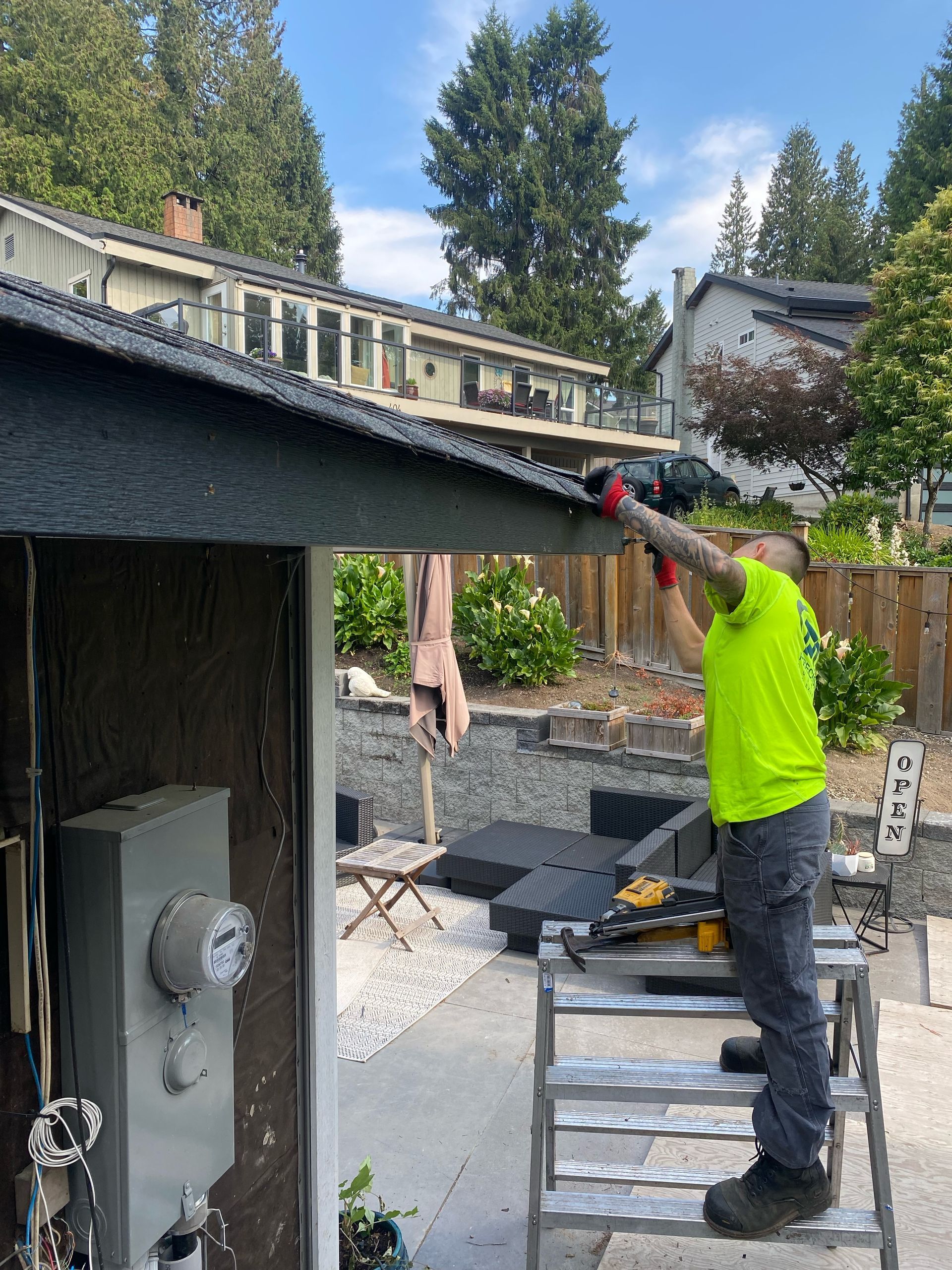 A man is standing on a ladder working on a roof.