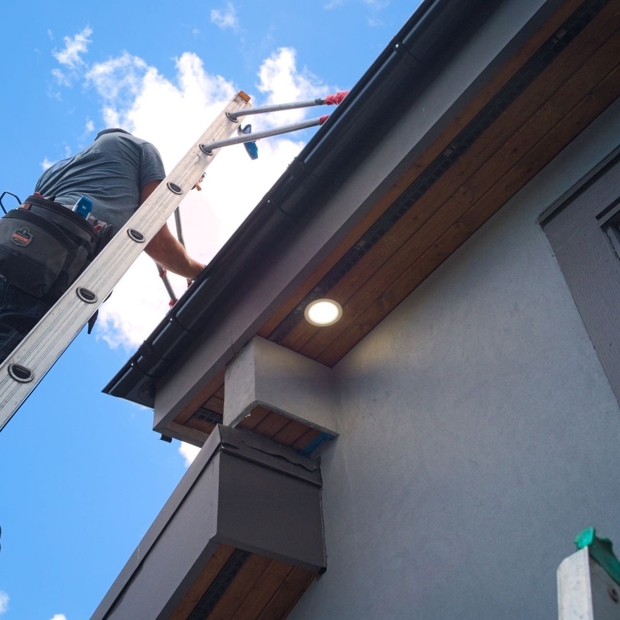 A man on a ladder working on a gutter