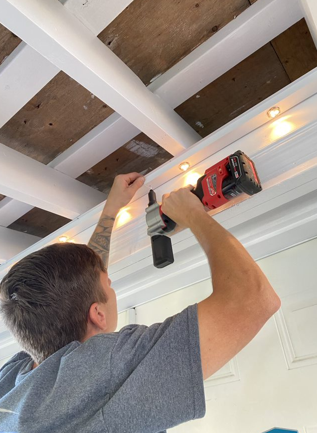 A man is working on a ceiling with a drill.
