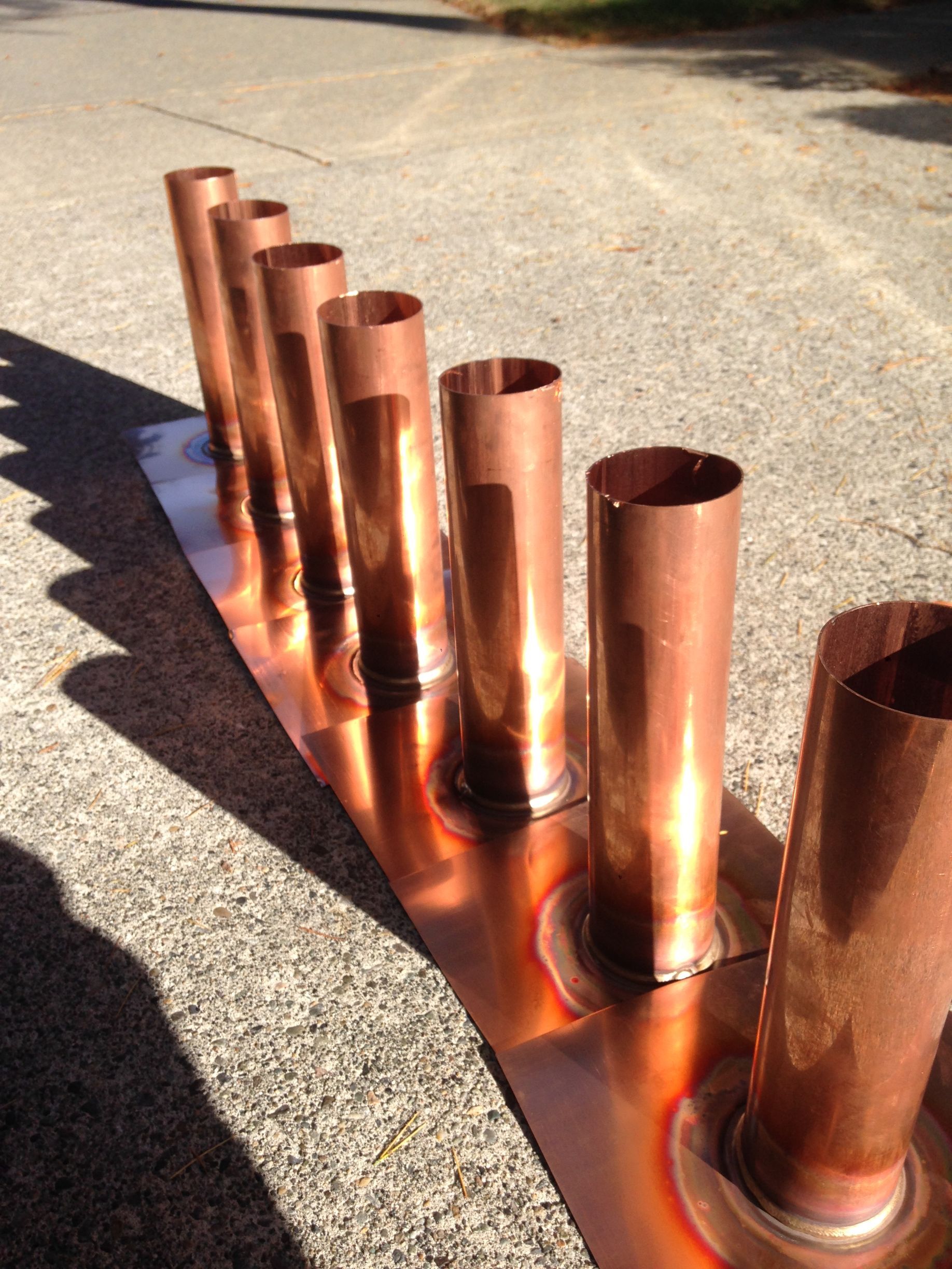 A bunch of copper pipes are lined up on the ground