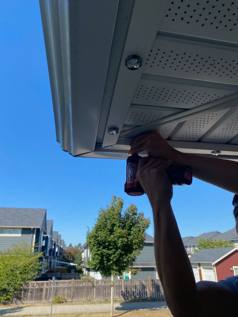 A man is working on a roof with a drill.