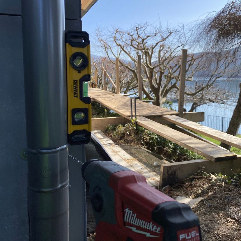 A red milwaukee drill is sitting next to a yellow level.