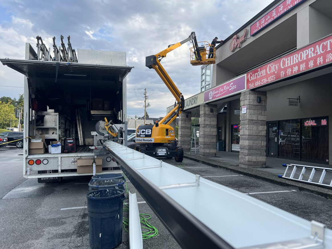 A truck is parked in front of a building with a crane attached to it.