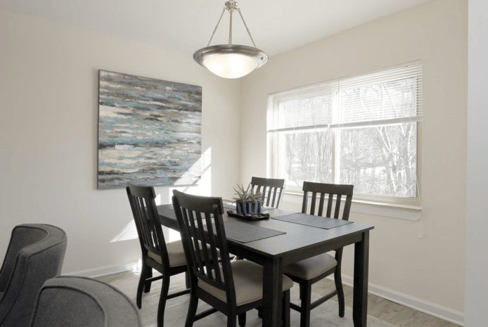 Dining room with a table, four chairs, artwork, and a window with blinds.