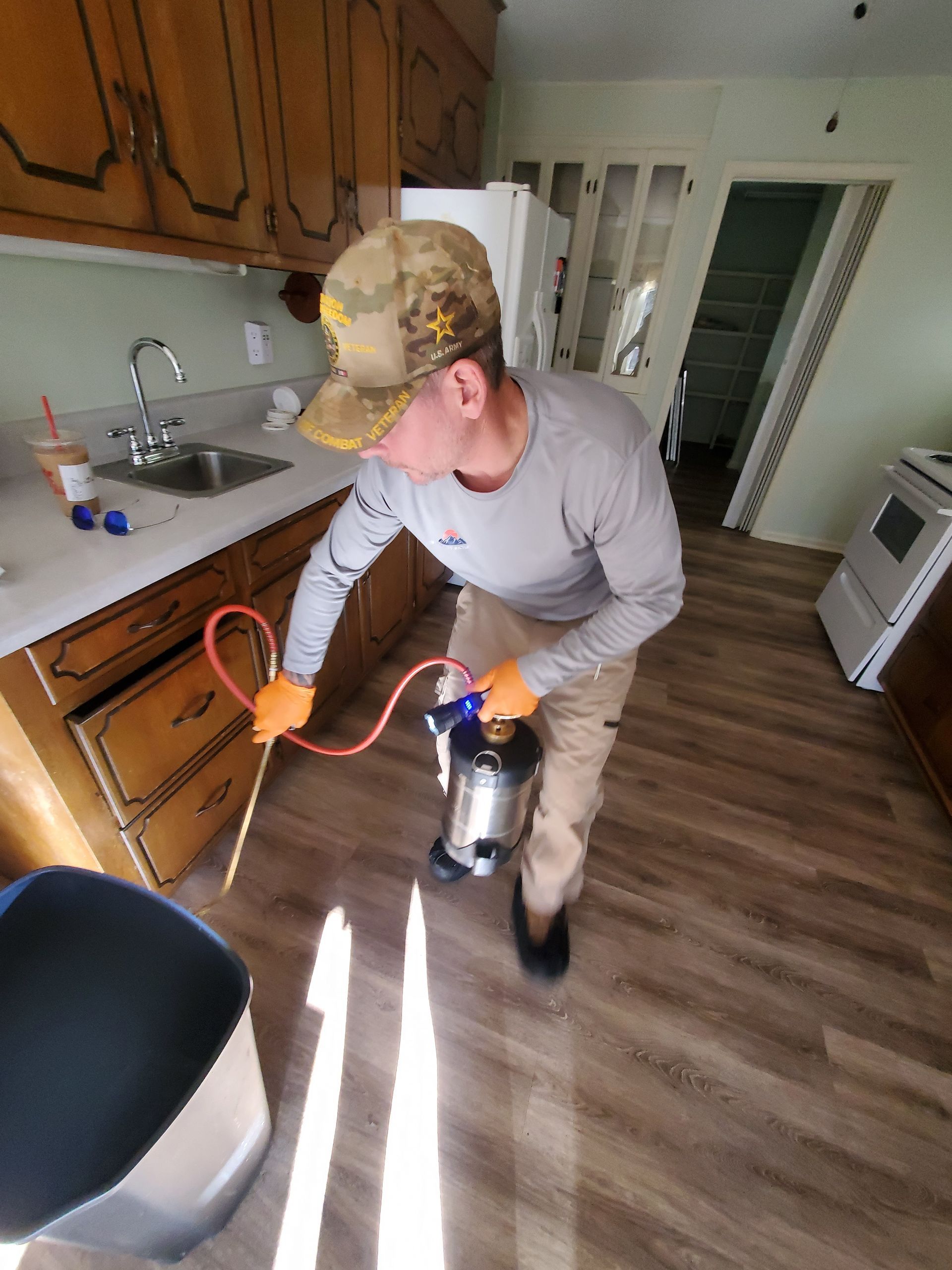 Person using a leaf blower in a kitchen, with orange extension cord and sunlight on the floor
