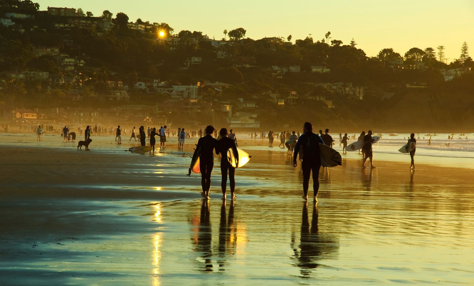 People walking on a wet beach at sunset, with reflections on the water and shoreline silhouettes. People walking on a wet beach at sunset, with reflections on the water and shoreline silhouettes.