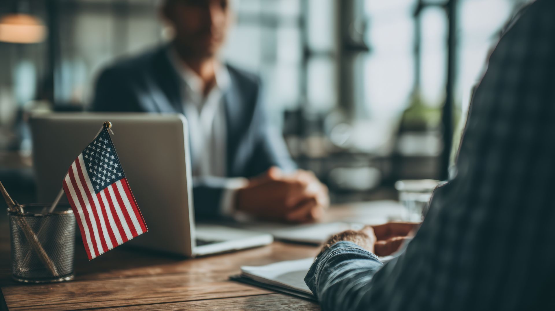 Immigration attorney consulting client in office with US flag laptop legal meeting scene today.