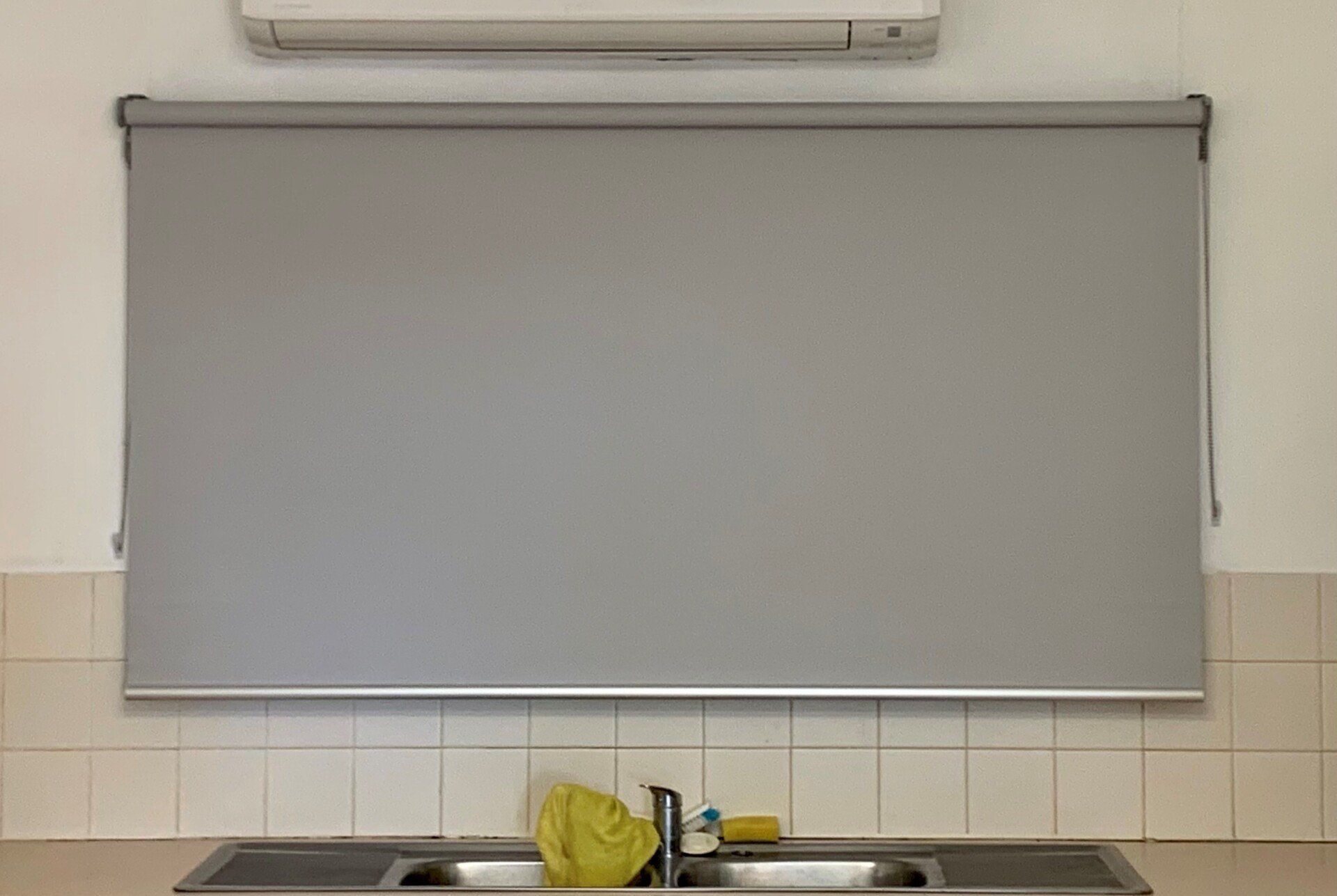 Grey Roller Blind Over a Sink. AC Unit Above — Alice Mobile Blinds in Ciccone, NT