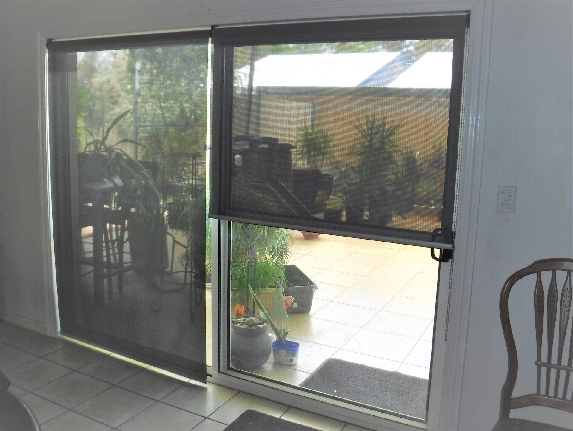 Sliding Glass Door with Dark Roller Blinds Partially Drawn — Alice Mobile Blinds in Ciccone, NT