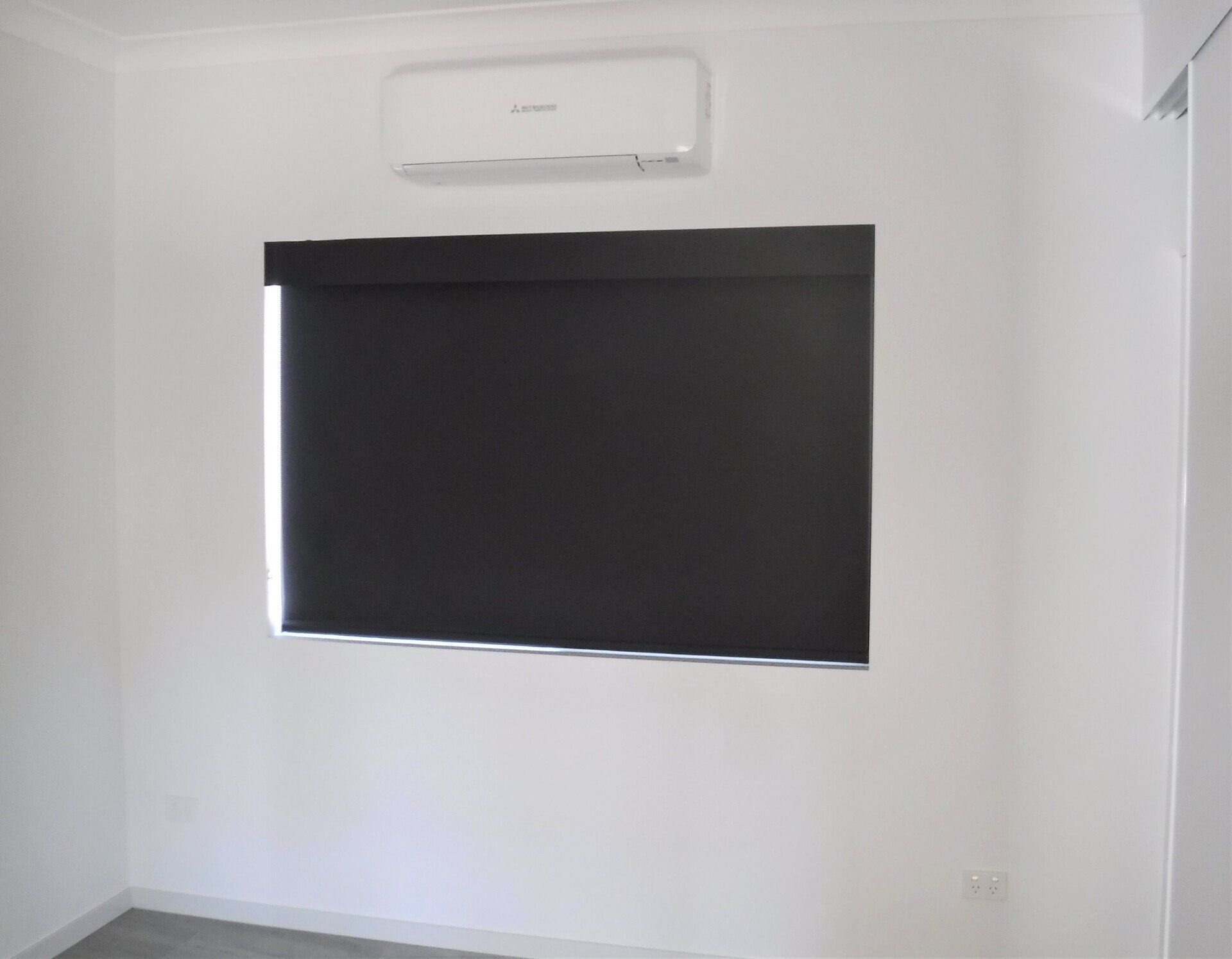 Black Roller Blind in A White-Walled Room — Alice Mobile Blinds in Ciccone, NT
