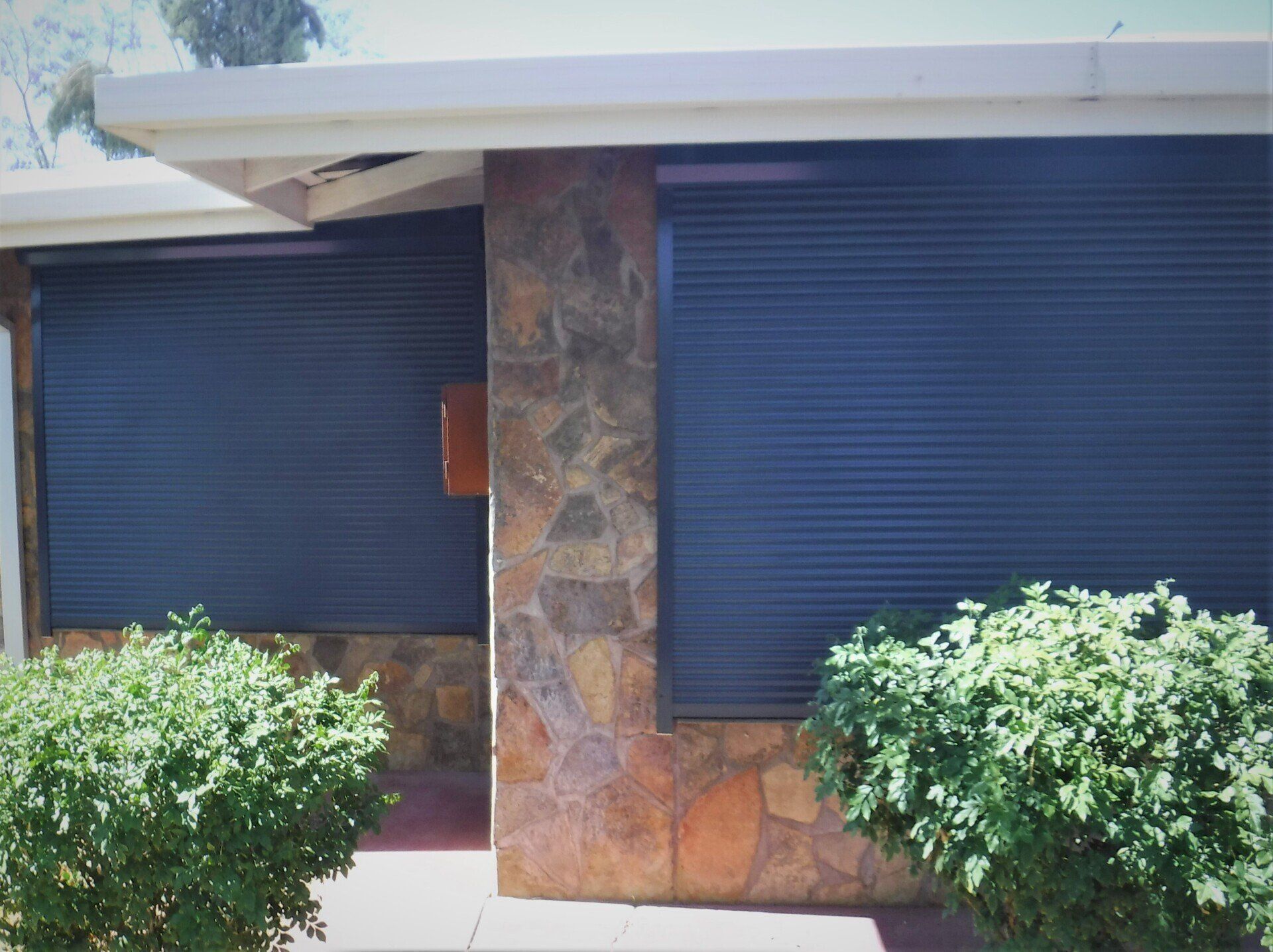 Exterior of A House with Two Windows Covered by Closed Blue Rolling Shutters — Alice Mobile Blinds in Ciccone, NT