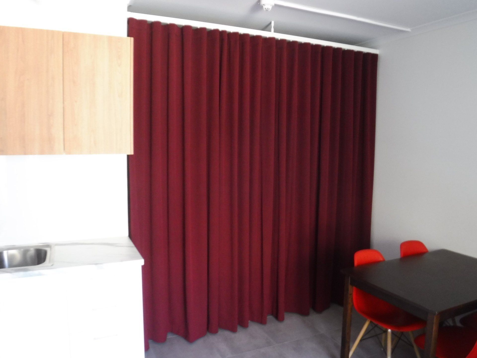 Red Curtains Divide a Small Space with A Kitchen — Alice Mobile Blinds in Ciccone, NT