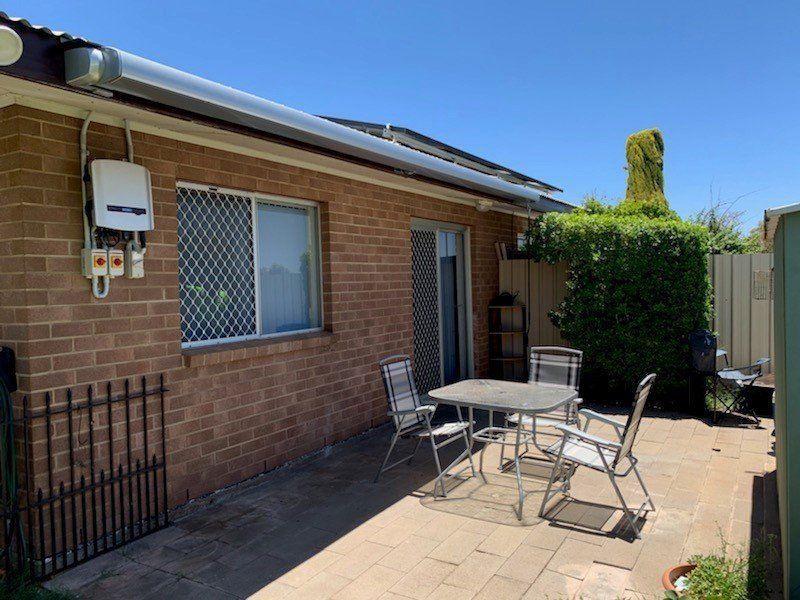 A Brick House Exterior with A Patio, Table, Chairs and Garden — Alice Mobile Blinds in Ciccone, NT