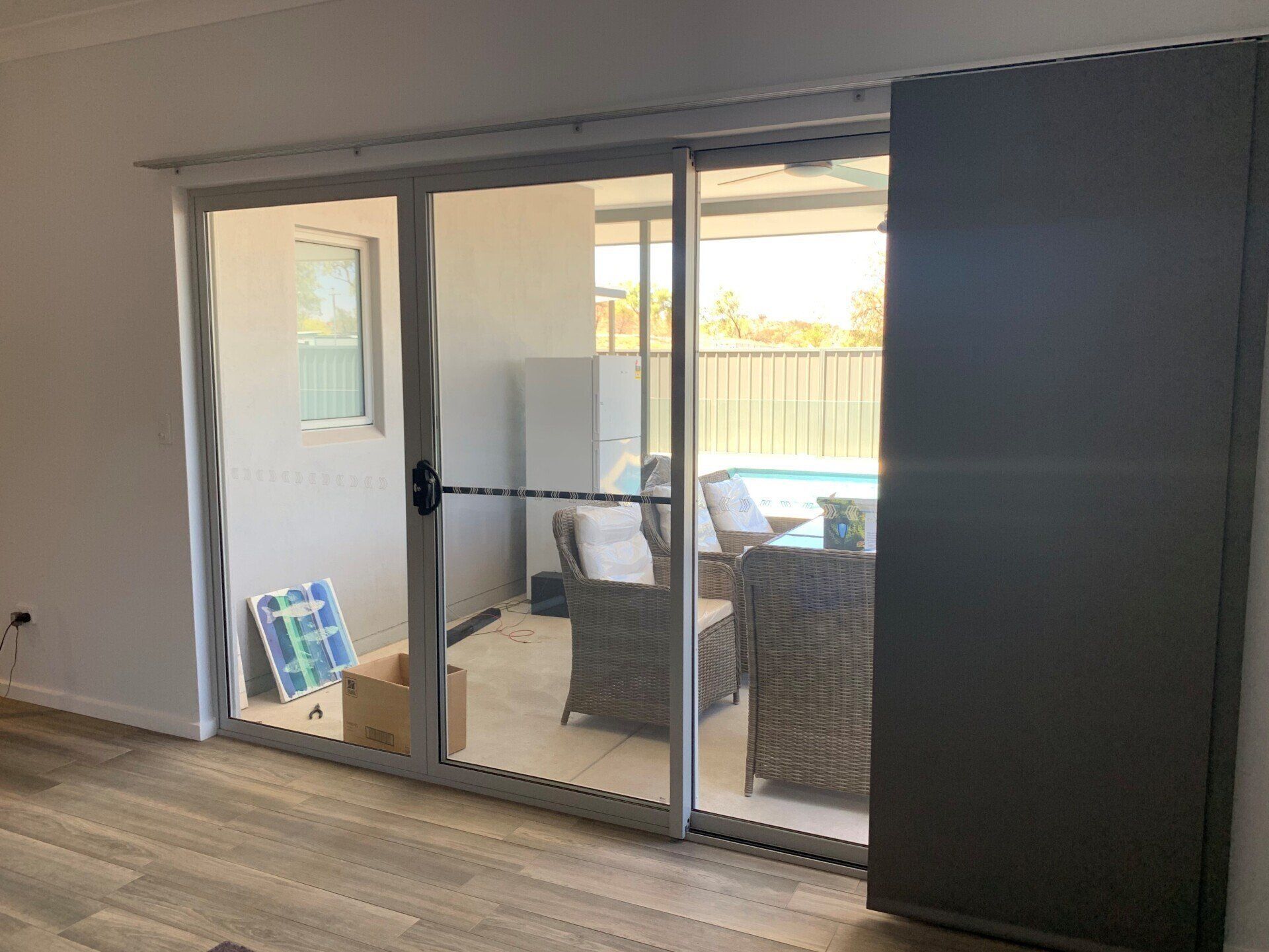 Sliding Glass Door Opens to Patio with Furniture and A Pool — Alice Mobile Blinds in Ciccone, NT